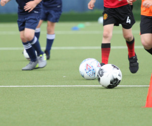 A player taking part in a football coaching drill A player taking part in a dribbling drill